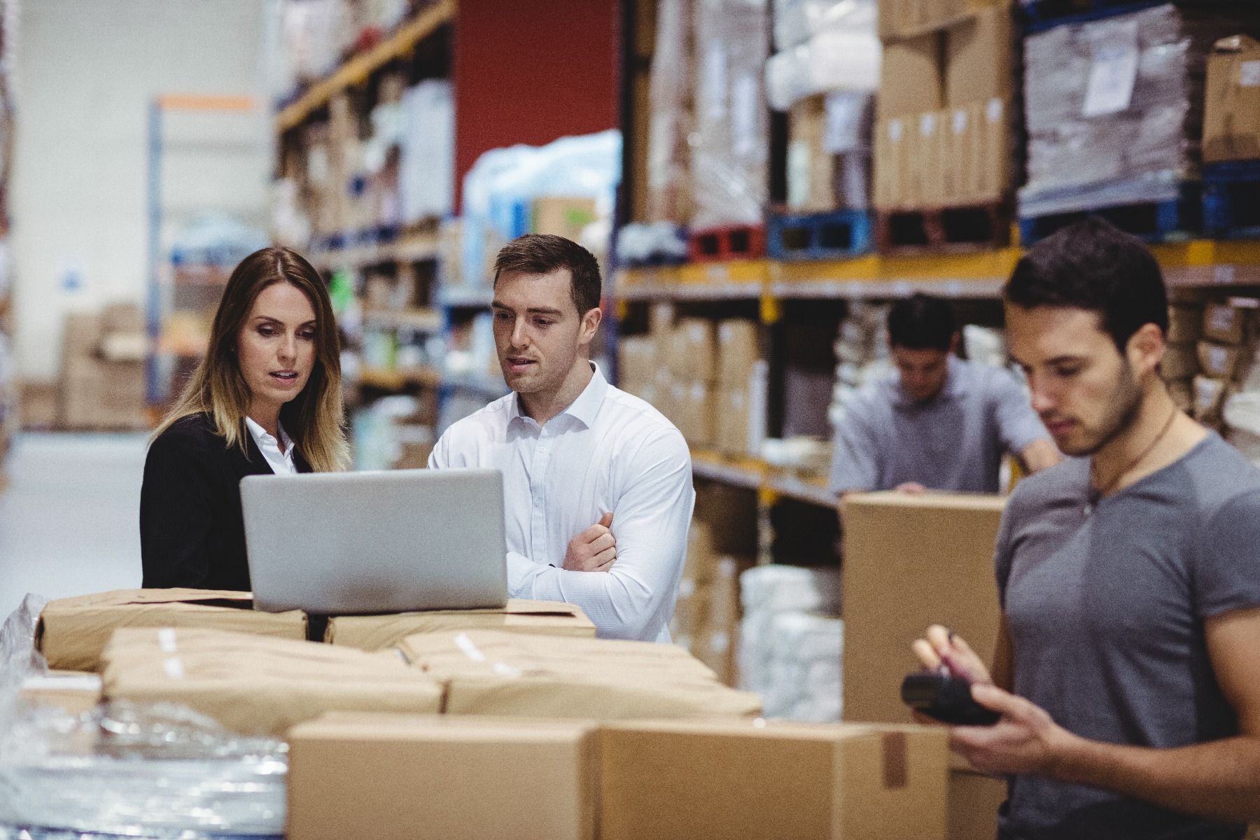 Warehouse team using laptop and phone to measure stock